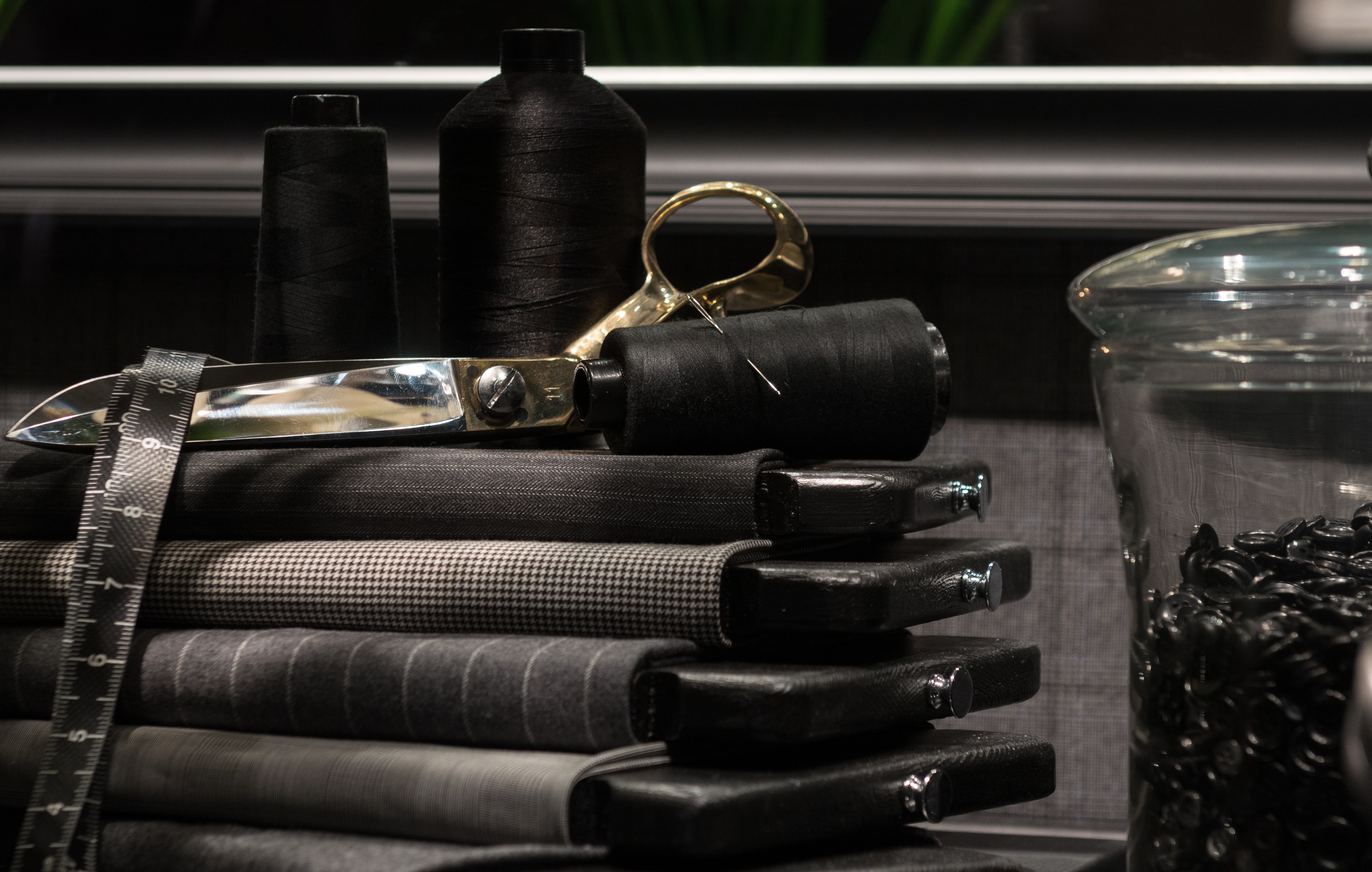 Tailor&rsquo;s tools — fabric swatches, scissors and thread